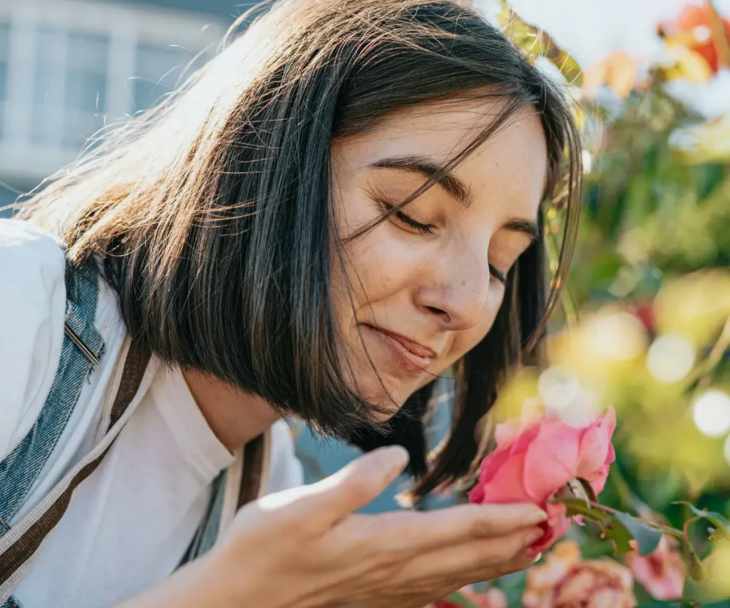 a woman smelling a rose in a garden