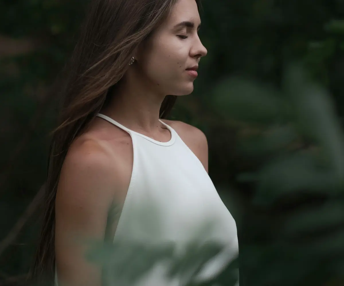 woman in white top taking deep inhale